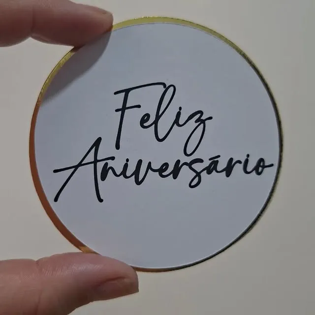 Adesivo redondo branco com borda dourada e a frase Feliz Aniversário